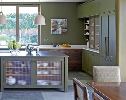 green kitchen with island and glass fronted cabinets